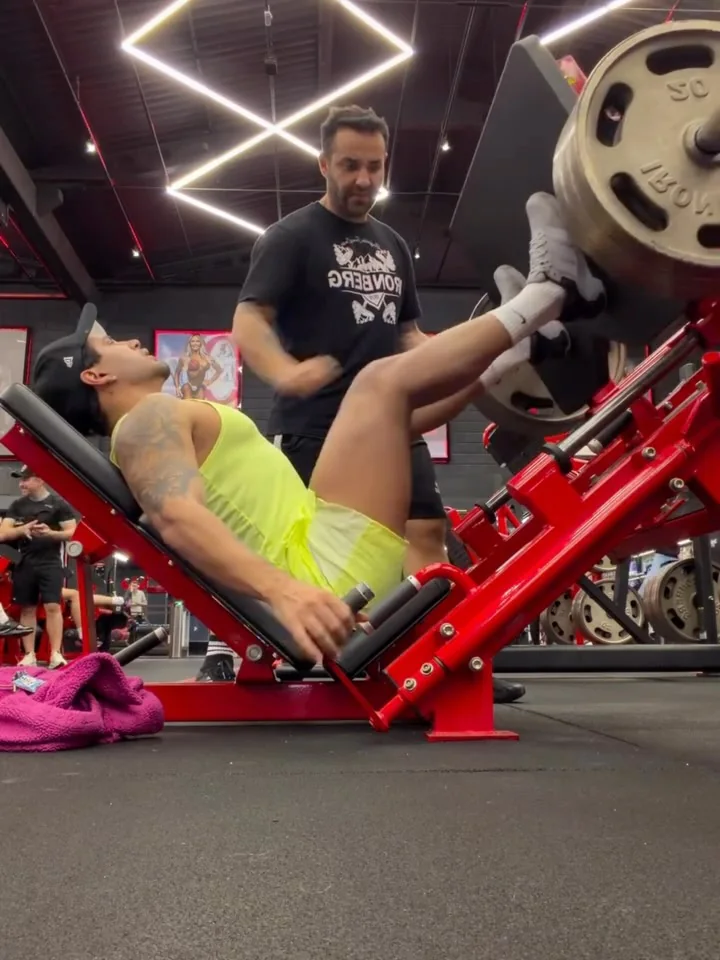 Gabriel Baú orientando uma aluna durante o leg press